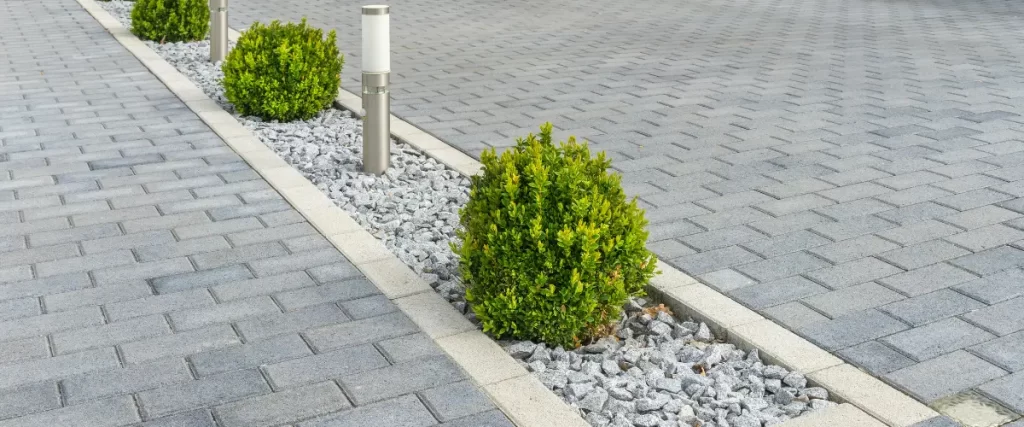 Paver driveway with decorative edging and neatly trimmed shrubs.