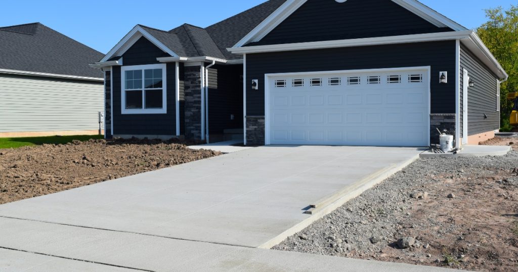 Freshly poured concrete driveway with clean edges and minimal landscaping.