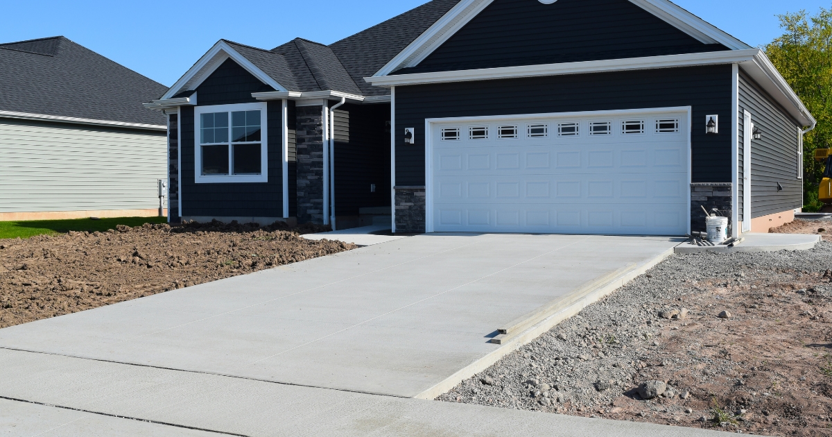 Freshly poured concrete driveway with clean edges and minimal landscaping.