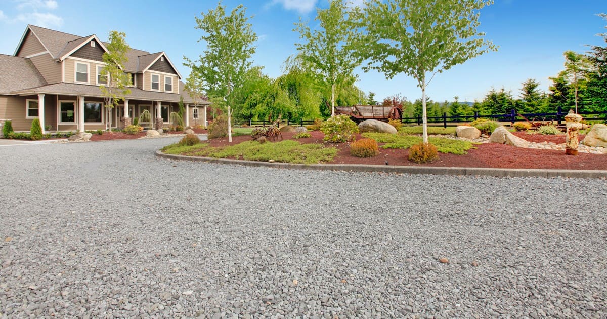 A wide residential landscaping view featuring a large grey stone path, demonstrating the best gravel for walkways in front of a house.